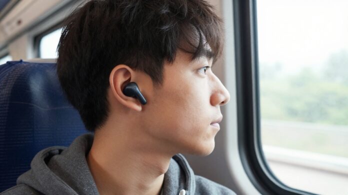 A person wearing discrete wireless earbuds while looking out a train window during a commute.
